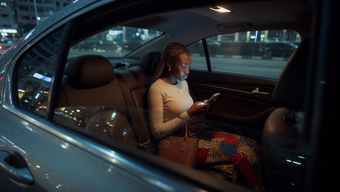Woman using her phone in the back seat of a car at night